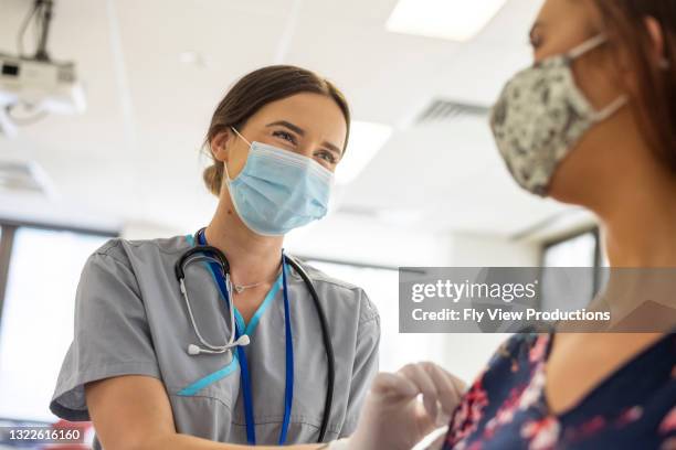 la enfermera amigable preps paciente antes de la vacuna contra covid-19 - tapabocas fotografías e imágenes de stock