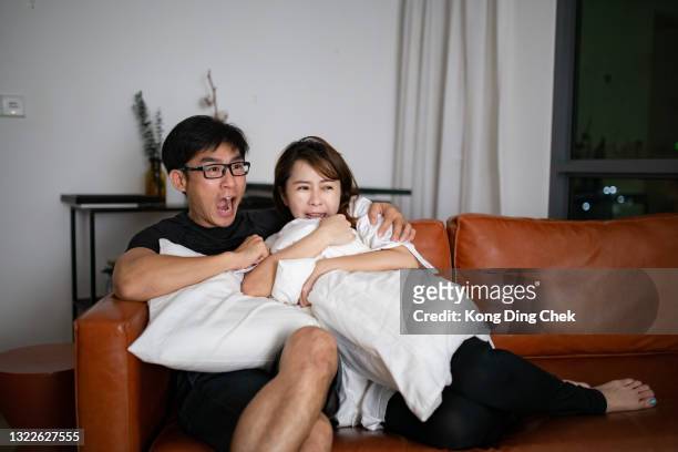 pareja china asiática viendo película de miedo en la televisión juntos en su casa - lovers 2020 film fotografías e imágenes de stock