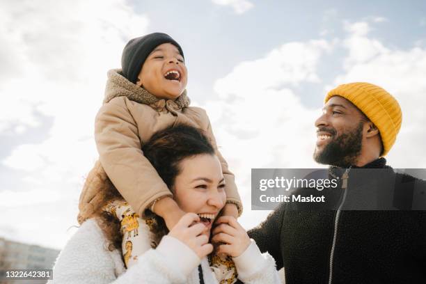 mother carrying son laughing with man against sky - vater mutter kind stock-fotos und bilder