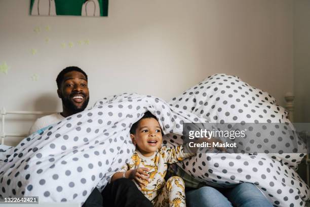 Smiling family with spotted blanket enjoying in bedroom