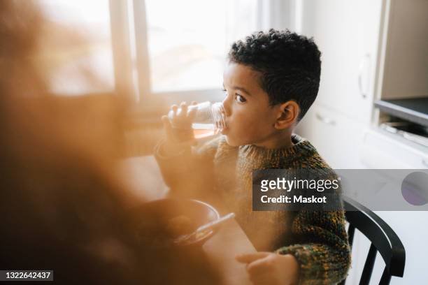 son drinking juice from jar in kitchen - routine bildbanksfoton och bilder