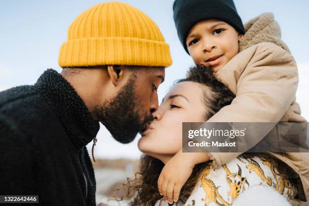woman carrying son on shoulders while kissing man - kissing mouth stock pictures, royalty-free photos & images