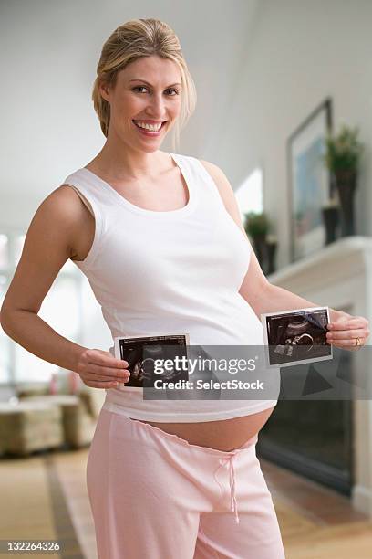 pregnant woman holding ultrasounds of twins - twin ultrasound stock pictures, royalty-free photos & images