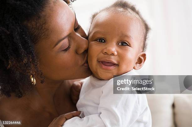mother kissing infant son - cheek kiss stock pictures, royalty-free photos & images