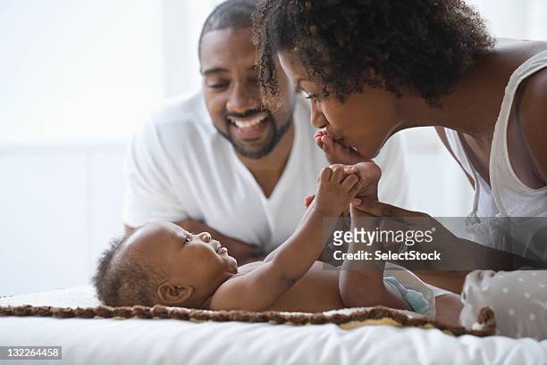 padre mirando al niño bebé y madre play - kissing feet fotografías e imágenes de stock
