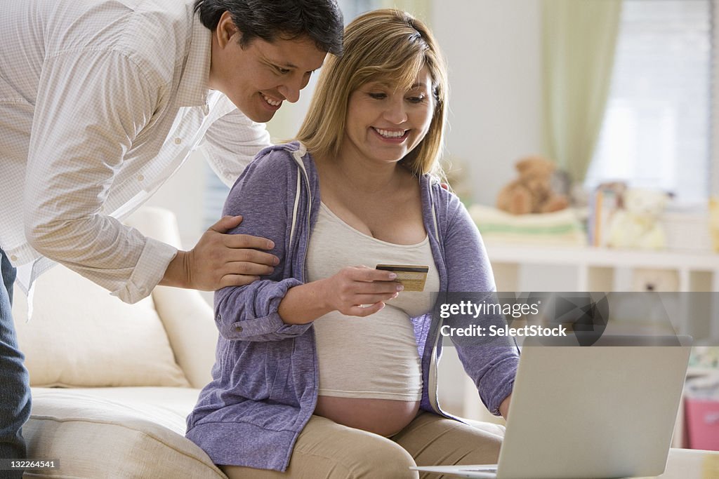 Pregnant woman and husband paying bills with credit card