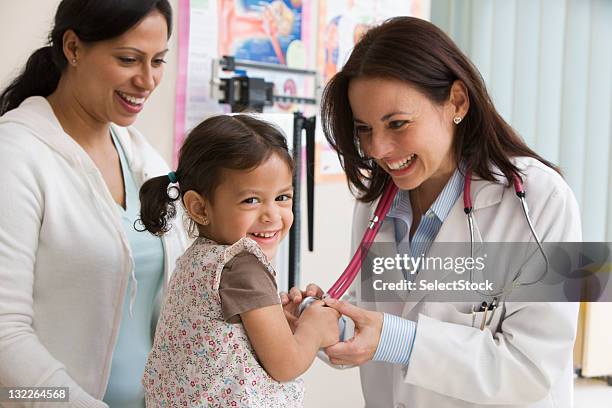 toddler girl laughing while doctor examines - kinderarts stockfoto's en -beelden