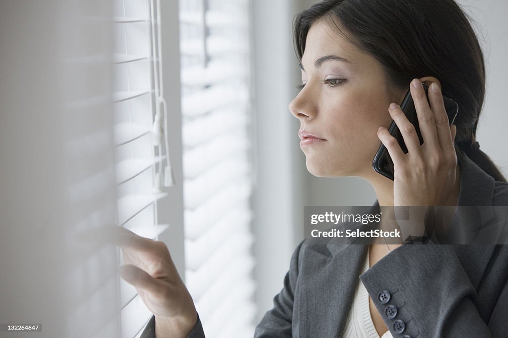 Geschäftsfrau mit Handy Blick aus dem Fenster werfen