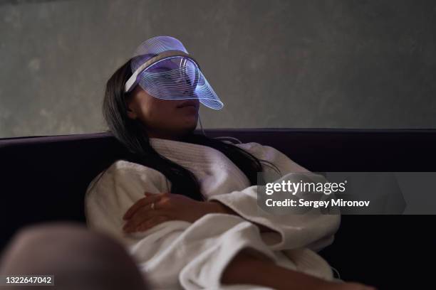 woman with led beauty mask on face - luce led foto e immagini stock