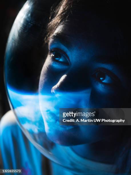 young astronaut wearing a space helmet and looking to the earth through the space shuttle window. space journey concept. - space travel vehicle fotografías e imágenes de stock