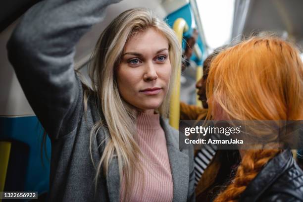 junge erwachsene blondine und rothaarige frauen pendeln in der londoner u-bahn - busy tube stock-fotos und bilder