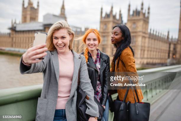 junge frauen in wintermänteln machen ein selfie vor dem palace of westminster in london - big ben black and white stock-fotos und bilder