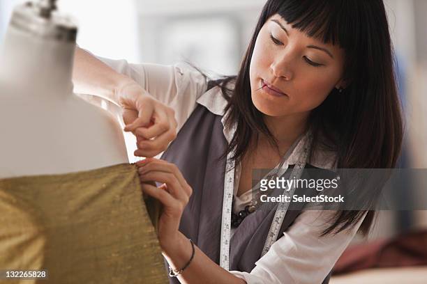 young female designer pinning fabric to mannequin - modeontwerper stockfoto's en -beelden