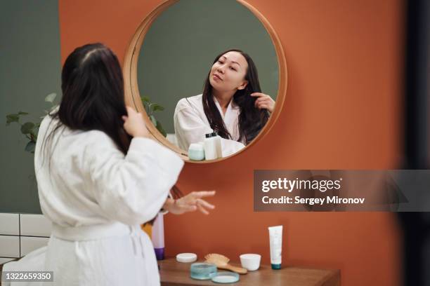 young asian woman brushing her hair - hair care stock pictures, royalty-free photos & images