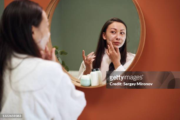 asian woman applying moisture cream at her face - body care and beauty stock pictures, royalty-free photos & images