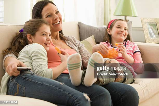 mother and daughters watching television - lying on back girl on the sofa stock pictures, royalty-free photos & images
