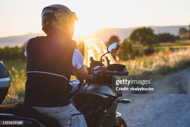 motociclista en la carretera rural al atardecer - moto fotografías e imágenes de stock