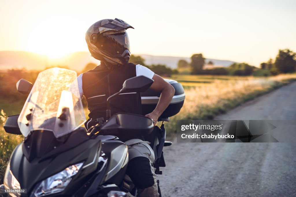 Man on motorcycle enjoys in ride at sunset