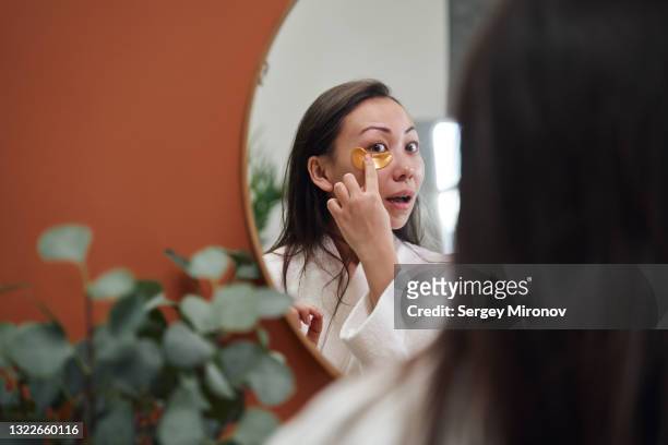 asian woman applying eye patchs - indulgence foto e immagini stock