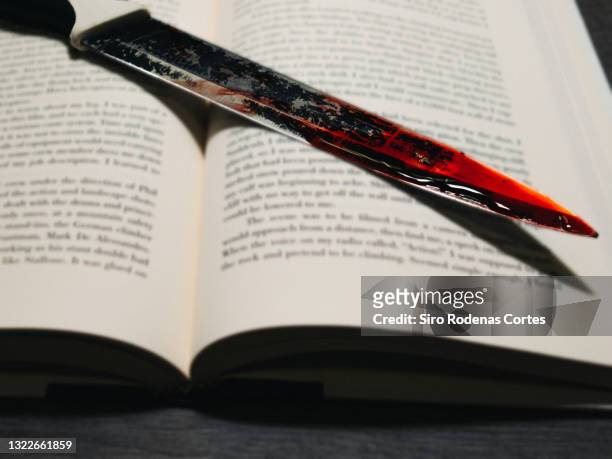 vignetted image of a bloody kitchen knife on a book as a concept of a detective novel - scary bloody 個照片及圖片檔