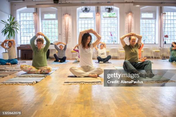 group of people stretching hands during yoga class - self improvement stock pictures, royalty-free photos & images