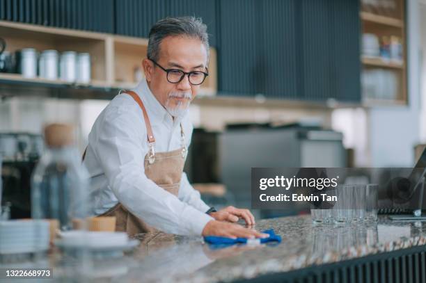 asian chinese cafeteria working senior man cleaning kitchen counter with towel - restaurant cleaning stock pictures, royalty-free photos & images