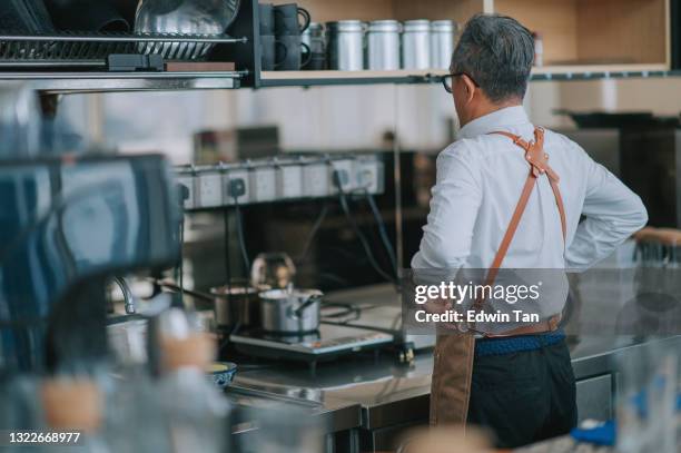 rückansicht asiatische chinesische senior mann kellner binden schürze immer lesen, um im kommerziellen küchencafé zu arbeiten - schürze mann rückansicht stock-fotos und bilder