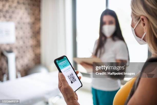 senior patient with smartphone showing vaccine passport in hospital. - display cabinet photos et images de collection