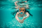 Underwater view of beautiful woman swimming in blue ocean water
