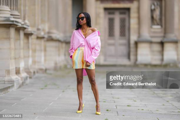 Emilie Joseph @in_fashionwetrust wears black sunglasses, silver earrings, a gold chunky necklace from Merbabe, a pale pink oversized boyfriend shirt...