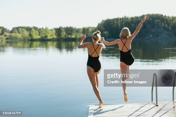 women jumping into lake from deck - johner images bildbanksfoton och bilder