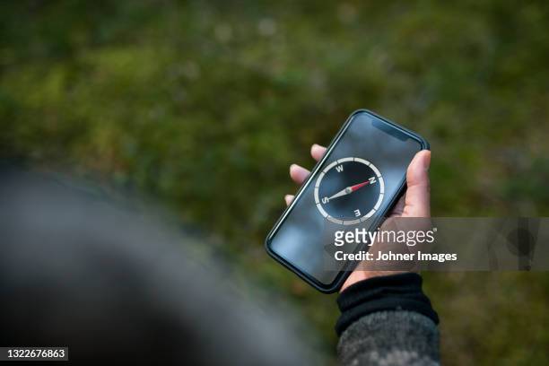 woman using compass on smart phone - brújula fotografías e imágenes de stock
