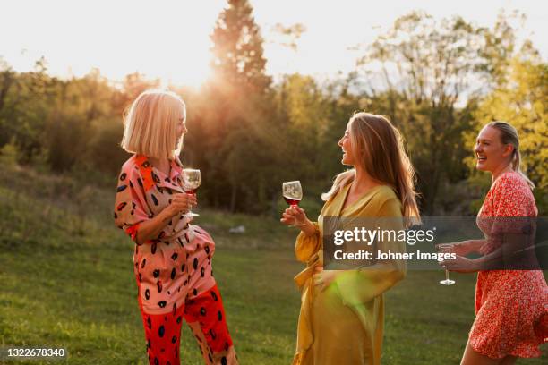 smiling female friends holding wine glasses in garden - wijn tuin stockfoto's en -beelden