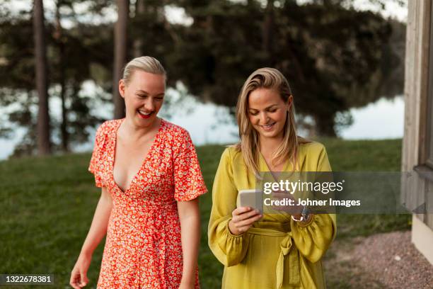 smiling female friends using smart phone - scandinavian woman blond stock pictures, royalty-free photos & images