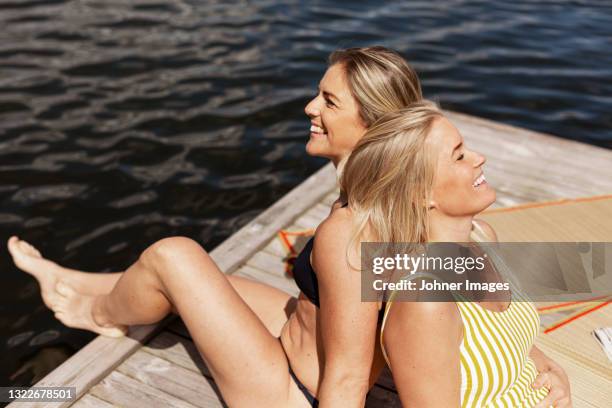 smiling female couple relaxing at lake - sunbathing stock pictures, royalty-free photos & images