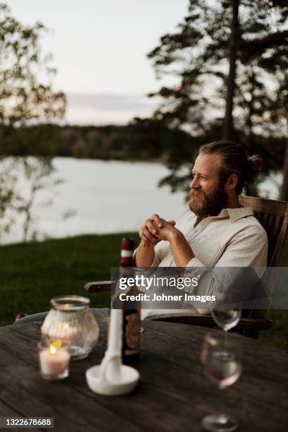 man sitting on porch at dusk - garden night photos et images de collection