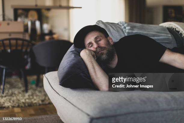 mature man sleeping on sofa - sofa stock-fotos und bilder