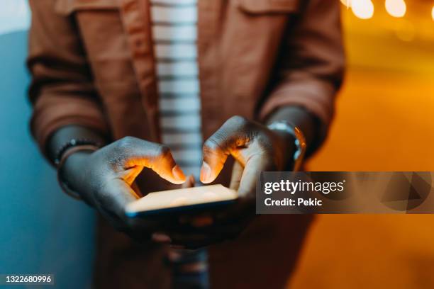 young unrecognisable man using typing on mobile phone at night - hand glow stock pictures, royalty-free photos & images