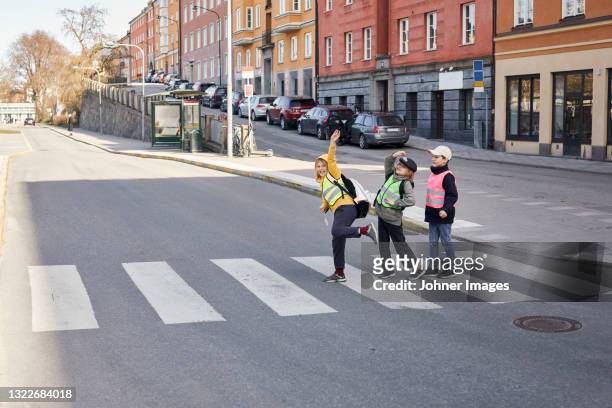 children crossing road together - zebrastreifen stock-fotos und bilder