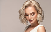 Portrait of beautiful looking young blonde woman with the middle length hair performed in elegant hairstyle.Elegance and hairstyling.