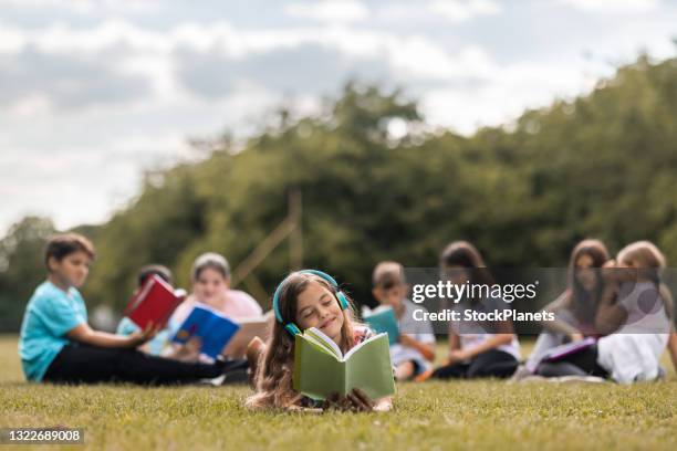 elementary students reading a book in public park - children only stock pictures, royalty-free photos & images