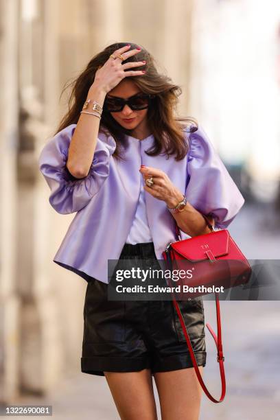 Therese Hellström wears a pale purple puffy shorts sleeves jacket, a white t-shirt, a gold white brown snake pattern leather bracelet, silver and...