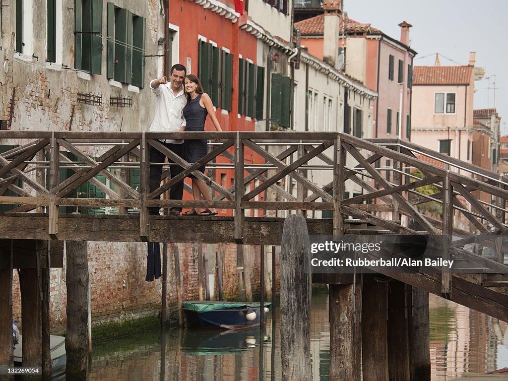 Italy, Venice, Romantic couple standing on footbridge over canal