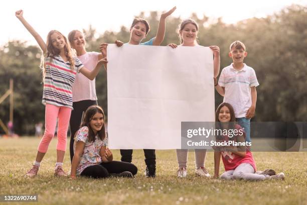 happy elementary students with blank paper outdoors - kids placard stock pictures, royalty-free photos & images