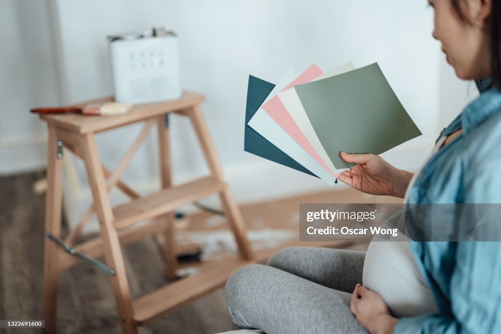 Pregnant Woman Renovating Nursery Room For Her Newborn Baby