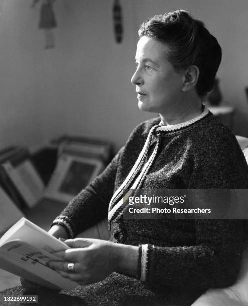 View of French author and philosopher Simone de Beauvoir as she reads a book, Paris, France, 1969.