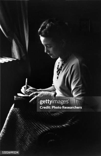 View of French author and philosopher Simone de Beauvoir as she writes, Paris, 1954.