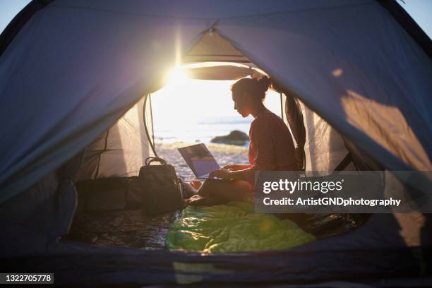 woman in tent using laptop at sunrise. - development camp stock pictures, royalty-free photos & images