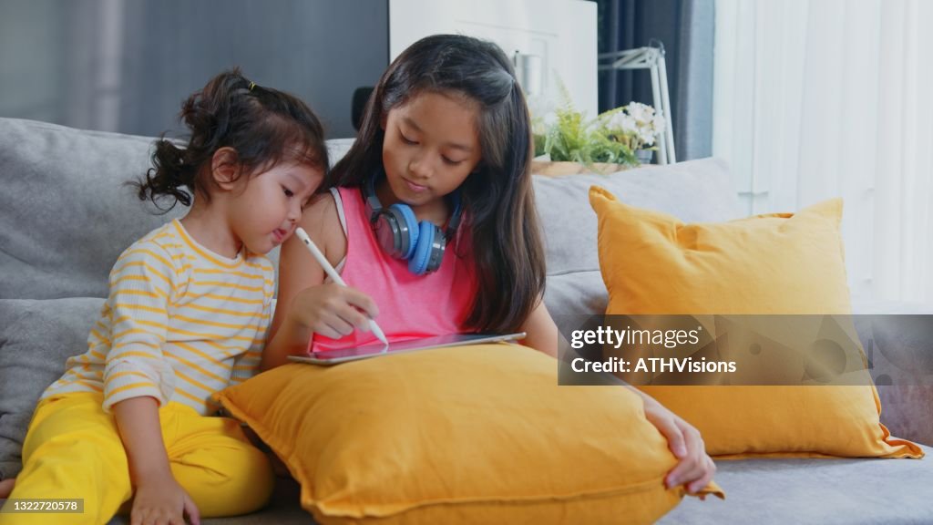 Bossy zuster teching peuter tekening foto op digitale tablet thuis