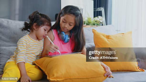 bossy sister teching toddler drawing picture on digital tablet at home - teching imagens e fotografias de stock